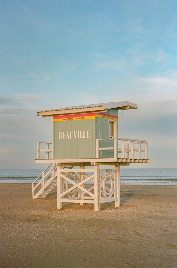 A pastel colored lifeguard station on a sandy beach.