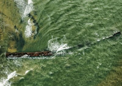 Waves crash over a submerged shipwreck at sea.