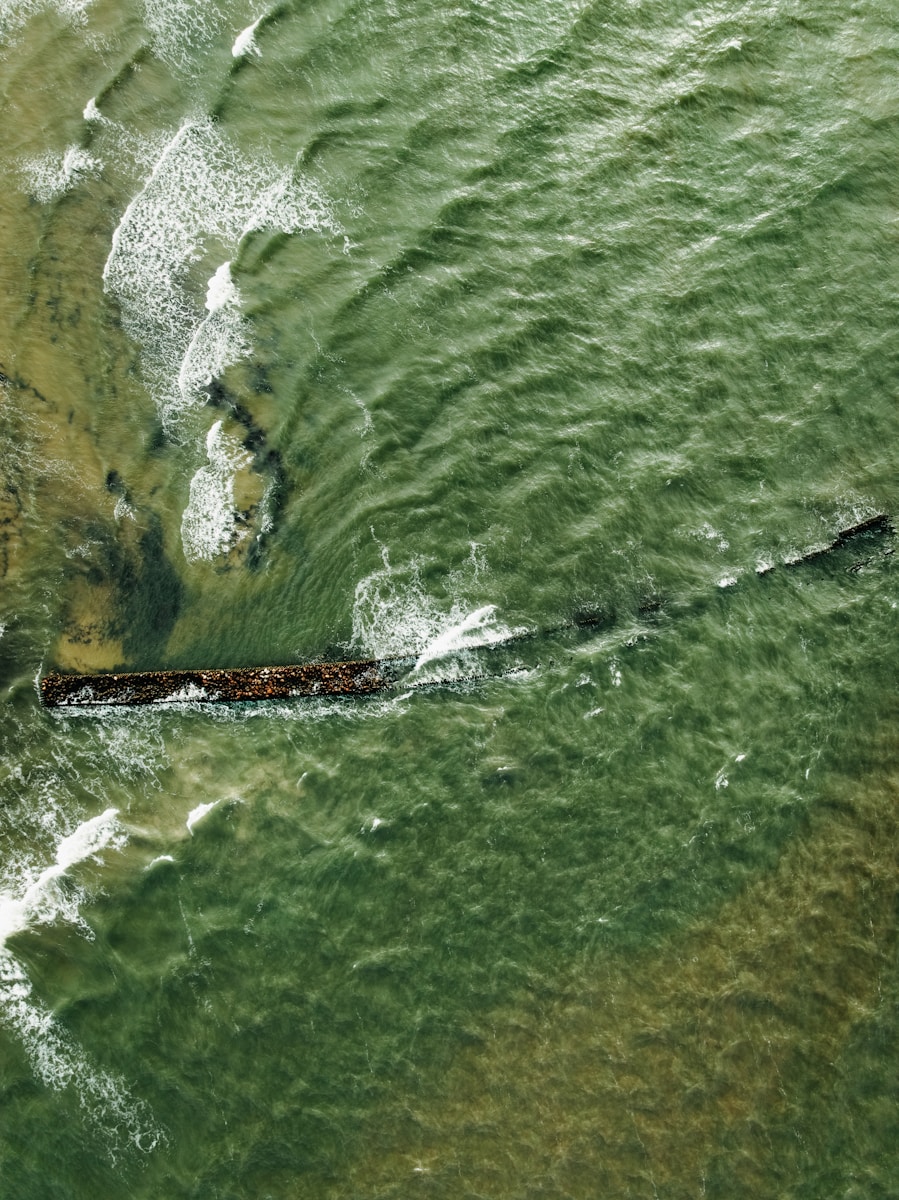 Waves crash over a submerged shipwreck at sea.
